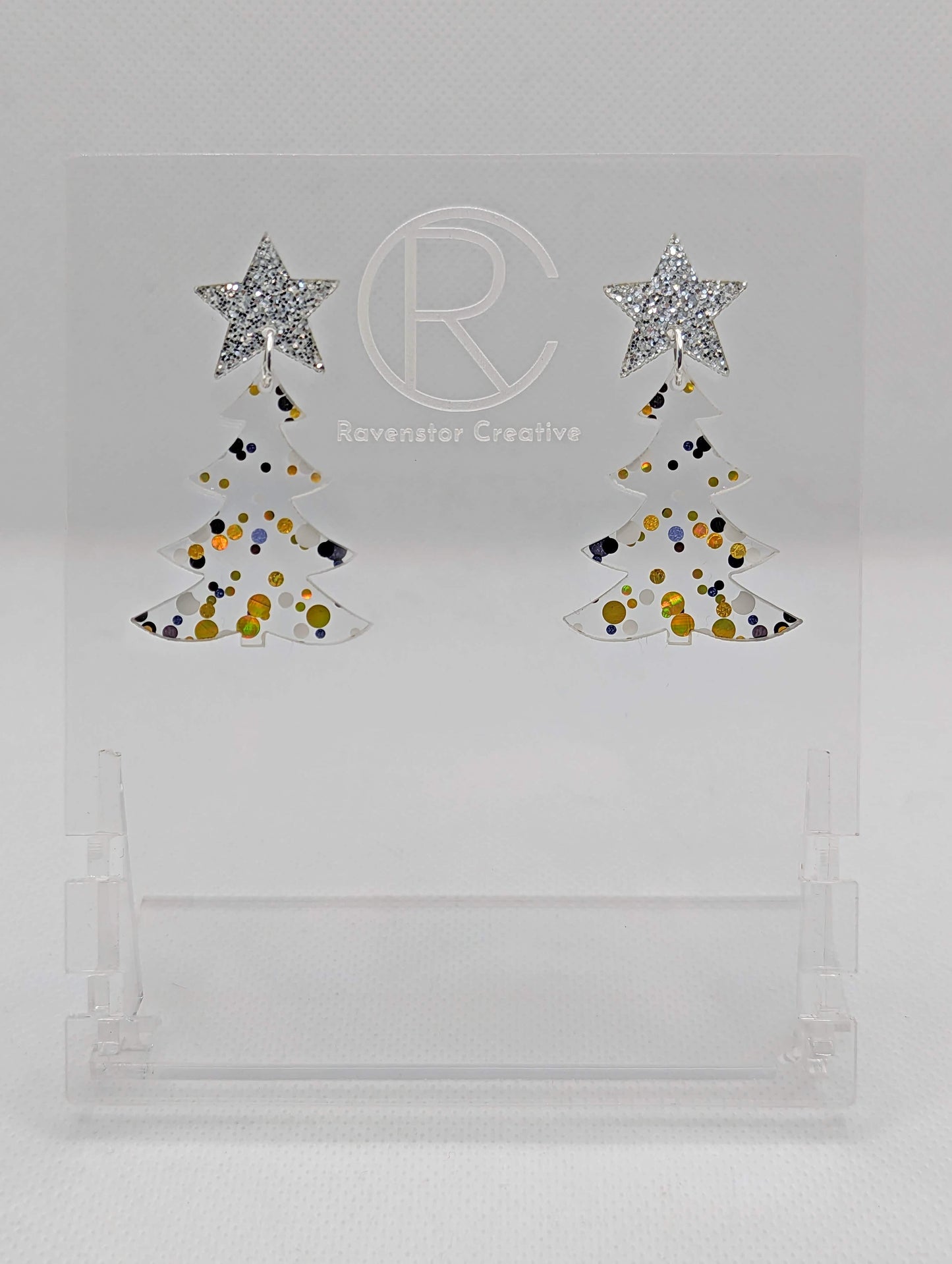A pair of acrylic Christmas tree earrings in two parts that have stud fixings. The studs are attached to a star with the tree dangling under They have a Silver Glitter star with a Lollipop Glitter Christmas Tree Dangling underneath.
