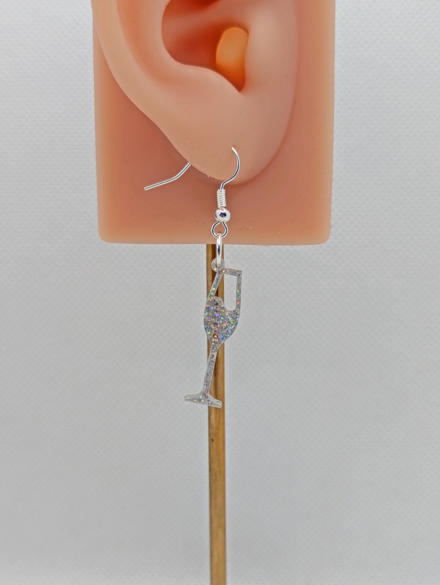 An image of a Champaign Glass Earring with a Silver ear wire hook fixing. These are ideal for a Hen Do or Bachelorette Party. The colour is Holographic Glitter. They are on an ear to show the size against a white background.