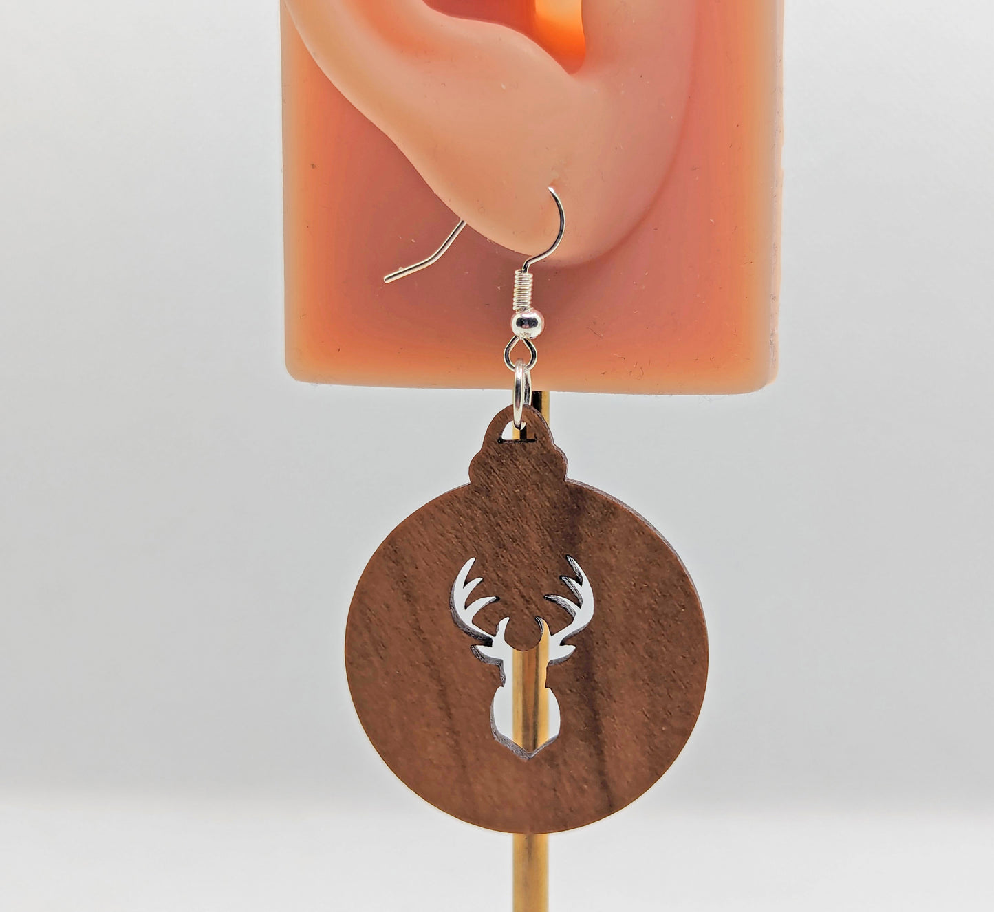 Image of a pair of earrings. They are Christmas / Xmas bauble shapes with a deers head cut out in Cherry Wood on an ear showing the size against a white background. They and have silver fixings.