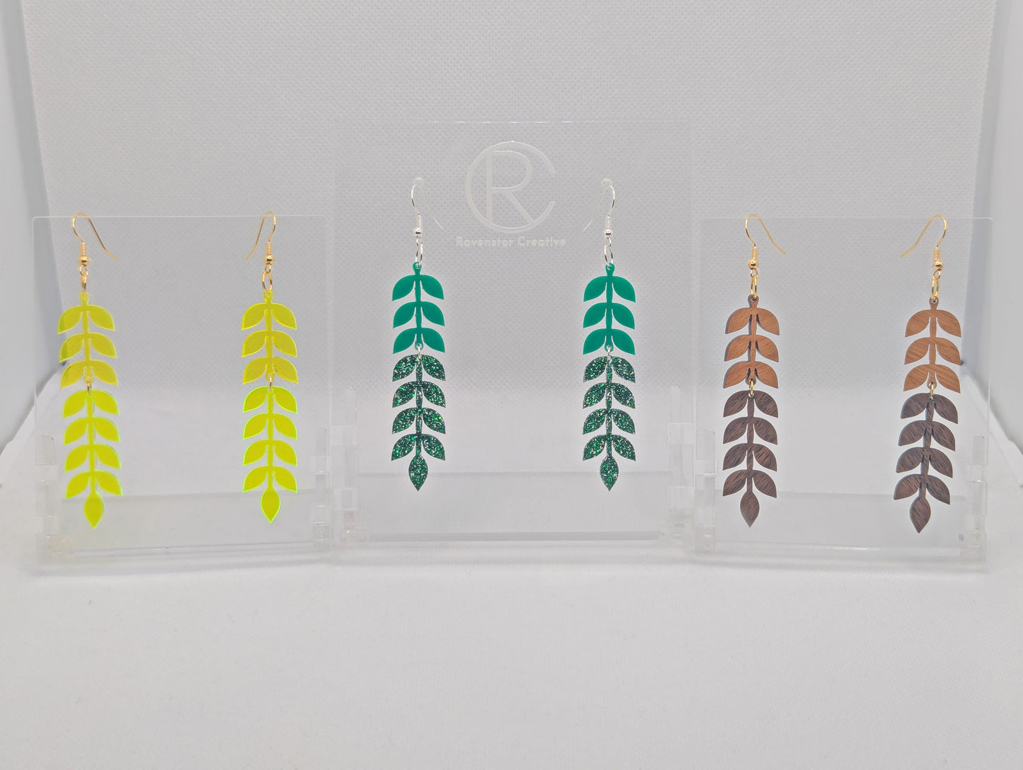 Three pairs of two part acrylic and wood drop earrings with ear wire hook fixings. They are vine leaves in two parts. The colours are Neon Orange top and yellow bottom, Green top and Green Glitter bottom, Cherry wood top and walnut wood bottom.