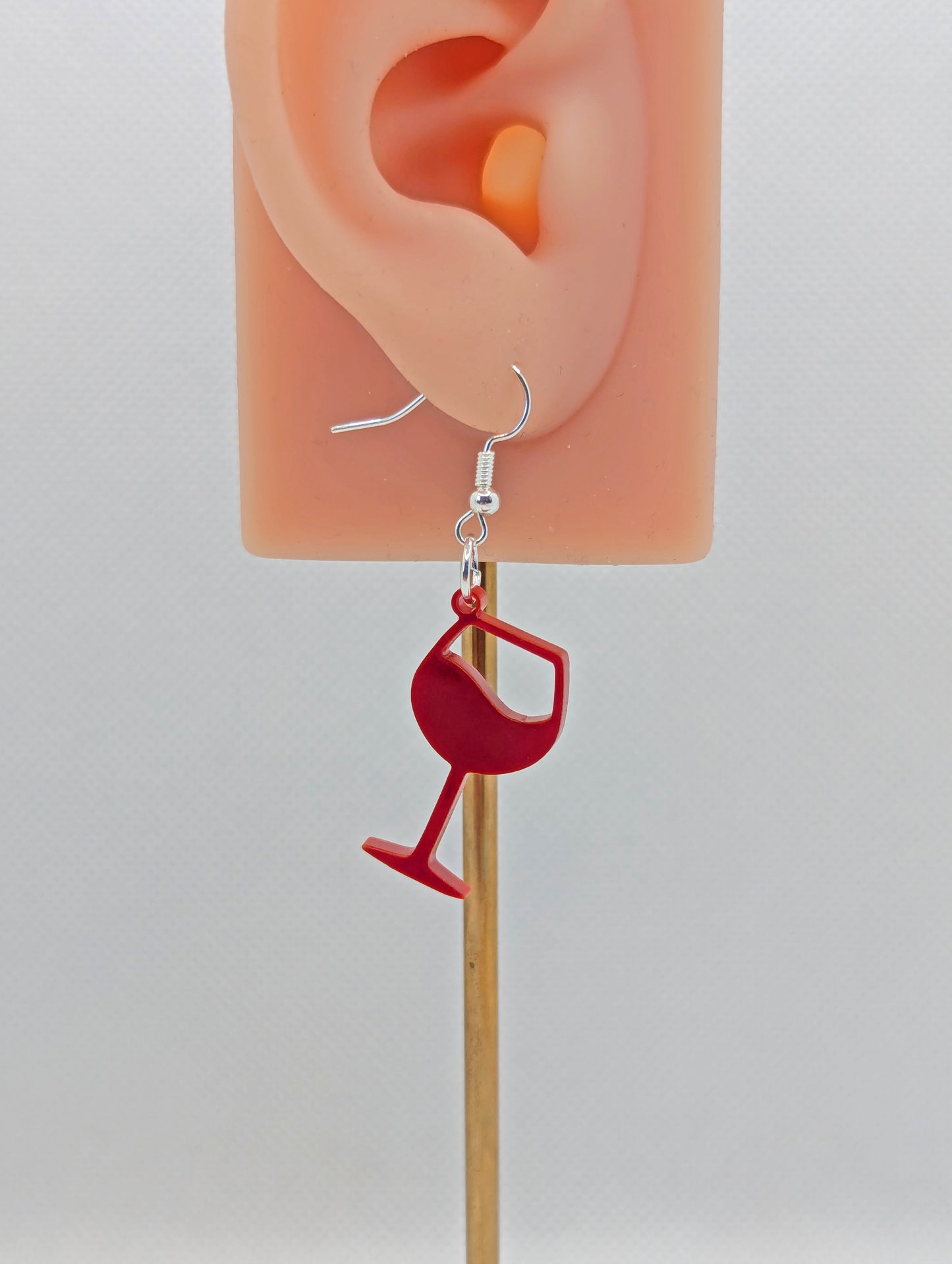 An image of a Wine Glass Earring with a Silver ear wire hook fixing. These are ideal for a Hen Do or Bachelorette Party. The colour is Maroon. They are on an ear to show the size against a white background.