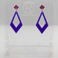 Shows a pair of 2 part earrings with stud fixings. The stud is on a small diamond shape with a larger kite shape dangling underneath. The colours are grape top and purple Kite. They are on a clear stand against a white backing