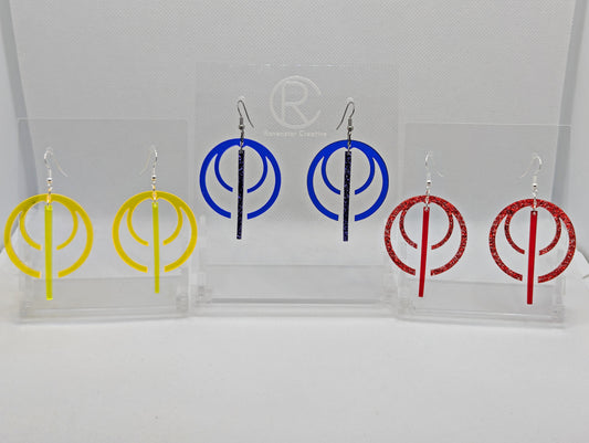 Shows three pairs of earrings that have ear wire hook fixings. They are large double hoops with a gap in the middle and joined at the top, in the gap is a thin dangly pendulum. The colours are Neon Yellow, Blue and Red Glitter.