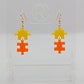 Shows a pair of acrylic earrings with silver ear wire hook fixings. They are Two Jigsaw Game Pieces with one dangling underneath. The colours are Yellow and Orange. They are against a white background on a clear stand.