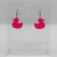 Shows a pair of acrylic earrings with black ear wire hook fixings. They are rubber ducky / duck shapes. The colour of them is hot pink. They are on a see through stand that has the Ravenstor Creative Logo and its against a white background.