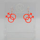 A pair of acrylic earrings in the shape of the Pride Double Male Gay LGBTQ symbol. They have Rose Gold ear wire hook fixings and the colour is Neon Pink.  They are on a clear stand with the Ravenstor Creative Logo on it against a white background.