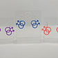 Three pairs of acrylic earrings in the shape of the Pride Double Male Gay LGBTQ symbol. They have ear wire hook fixings and the colours are Purple, Royal Blue Glitter and Neon Pink. They are on clear stands against a white background.