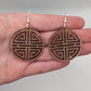 Shows a pair of Geometric Korean Inspired Circle earrings with an intricate pattern like a maze on a hand showing the size against a white background, they are two finger widths in length and two wide. They are Walnut wood and have silver fixings.