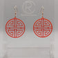 Shows a pair of acrylic earrings that have rose gold ear wire hook fixings. They are Geometric Korean Inspired Circle earrings with an intricate pattern like a maze. They are neon pink colour and are against a white background on see through stand.