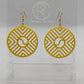 Shows a pair of Circle earrings that have gold ear wire fixings. They are Geometric Chevron designs with a yin and yang in the centre. They are made from yellow Acrylic. They are against a white background on see through stands.