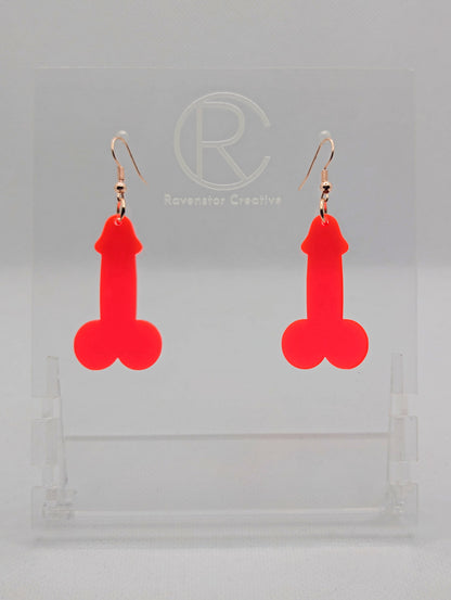 Image of a pair of earrings shaped like a Penis and Balls with Rose Gold ear wire hook fixings. These are ideal for funny Hen Dos or Bachelorette parties. The colour is Neon Pink and they are on clear stands against a white background.