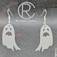 Shows a pair of earrings with silver ear wire hook fixings. They are spooky moaning ghost shapes. The colour of them is grey. They are on a see through stand that has the Ravenstor Creative Logo and its against a dark background.