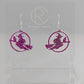 A pair of acrylic earrings with silver Ear wire hook fixings on a white background, they are a circle with a scene cut out of a witch on her broom with a cat perched on the broom. The colour is a pretty pink glitter.