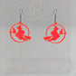 A pair of acrylic earrings with black Ear wire hook fixings on a white background, they are a circle with a scene cut out of a witch on her broom with a cat perched on the broom. The colour is a Neon Pink.