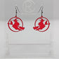 A pair of acrylic earrings with black Ear wire hook fixings on a white background, they are a circle with a scene cut out of a witch on her broom with a cat perched on the broom. The colour is a spooky translucent Red.