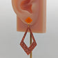 Shows a 2 part earring with stud fixings. The stud is on a small diamond shape with a larger kite shape dangling under on an ear showing thier size. The colours are orange for the top and copper glitter for the large kite shape.