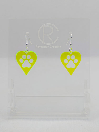 Shows a pair of earrings that have Silver ear wire hook fixings. They are hearts with a dog paw cut out of the middle, perfect for the puppy lover. The colour of them is Neon Green. They are on see through stands. Against a white background.