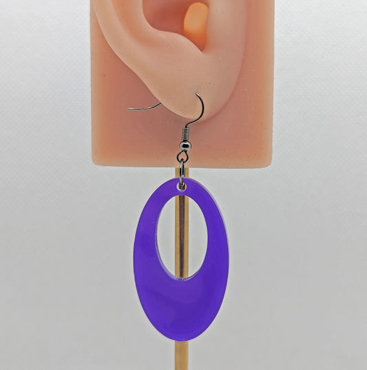 Image of an Oval shaped Hoop earring on an ear showing the size against a white background. It is made from purple acrylic and have black ear wire hook fixings.