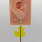 Image of a rubber ducky / duck shaped earring on an ear showing the size against a white background. They are neon yellow and have silver ear wire hook fixings.