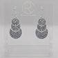 An image of snowman earrings with silver ear wire hook fixings. They are in three parts that dangle. They are made from Silver glitter acrylic and are on a clear stand with the ravenstor creative logo on it against a white background