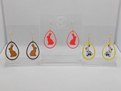 Three pairs of two part drop earrings with ear wire hook fixings. They are an egg shaped frame with a Bunny Rabbit dangling inside. The colours are Cherry Wood Bunny and Walnut Wood Egg, Neon Pink Bunny Sherbet Pink Egg, Lollipop Glitter and Yellow.