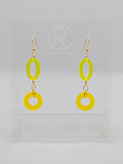 A pair of two part drop earrings with Gold ear wire hook fixings. They are an oval with a circle dangling underneath joined by three Gold jump rings. The colours are Neon Yellow for the oval and Neon Orange for the circle.