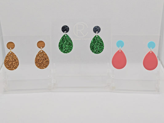 An image of three pairs of stud earrings, They are a circle at the top and a larger teardrop shape dangling underneath. The colours are Silver Black Glitter and Green Glitter, Cherry Wood and Copper Glitter, and Spearmint and Sherbet Pink.