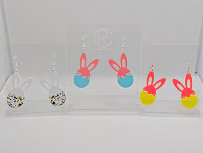 Three pairs of Drop earrings in two parts. The top part are bunny ears and the bottom is a broken egg. The colours are White ears and Lollipop Glitter for the egg. Sherbet Pink ears and Spearmint egg, Neon Pink ears and Neon Orange Egg.