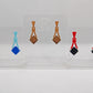 Image of three pairs of earrings. The design is a thin elegant top that forks out to support a diamond shape dangling under it. They are Spearmint and Blue, Red and Black Silver Acrylic and Cherry and Walnut Wood.