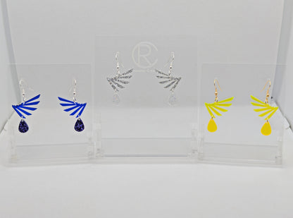 Three pairs of two part drop earrings with ear wire hook fixings. Each one is a single wing with a teardrop balancing underneath it. The colours are Translucent Blue and Purple Glitter, Silver Glitter and Clear Sparkle, Neon Yellow and Neon Orange.